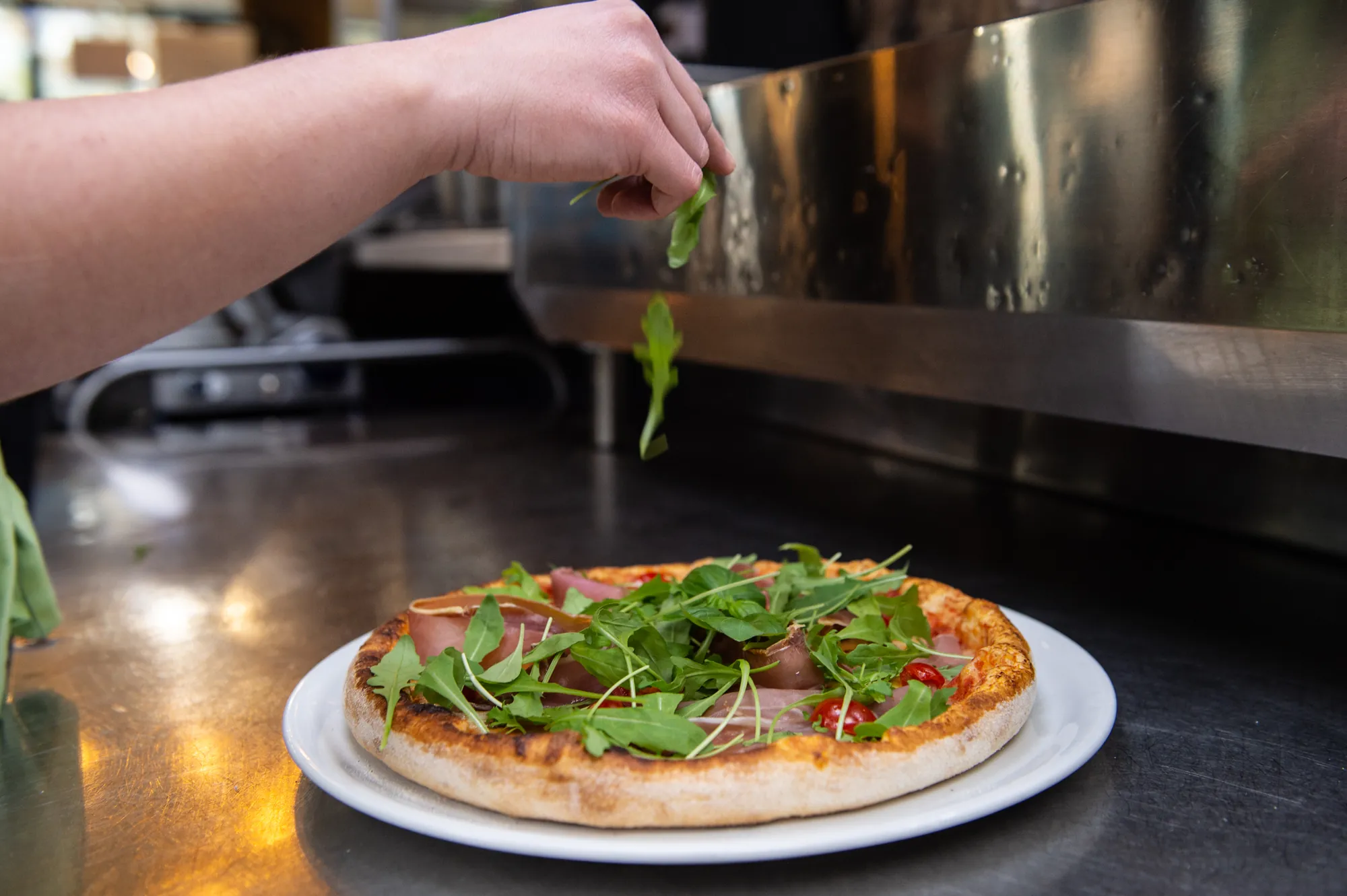Pizza Pizz'à Vitto garnie de roquette fraîche en cuisine